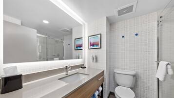A modern bathroom with a large mirror, a sink, a toilet, and a shower.