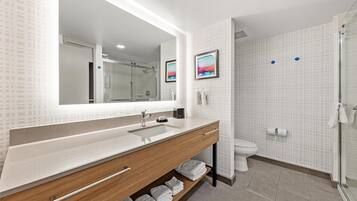 A modern bathroom with a large mirror, a sink, a toilet, and a shower area.