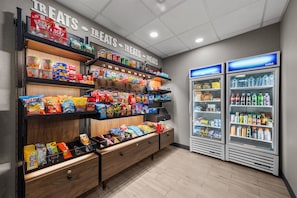 A snack aisle with various packaged snacks and a refrigerated section with bottled water and soft drinks.
