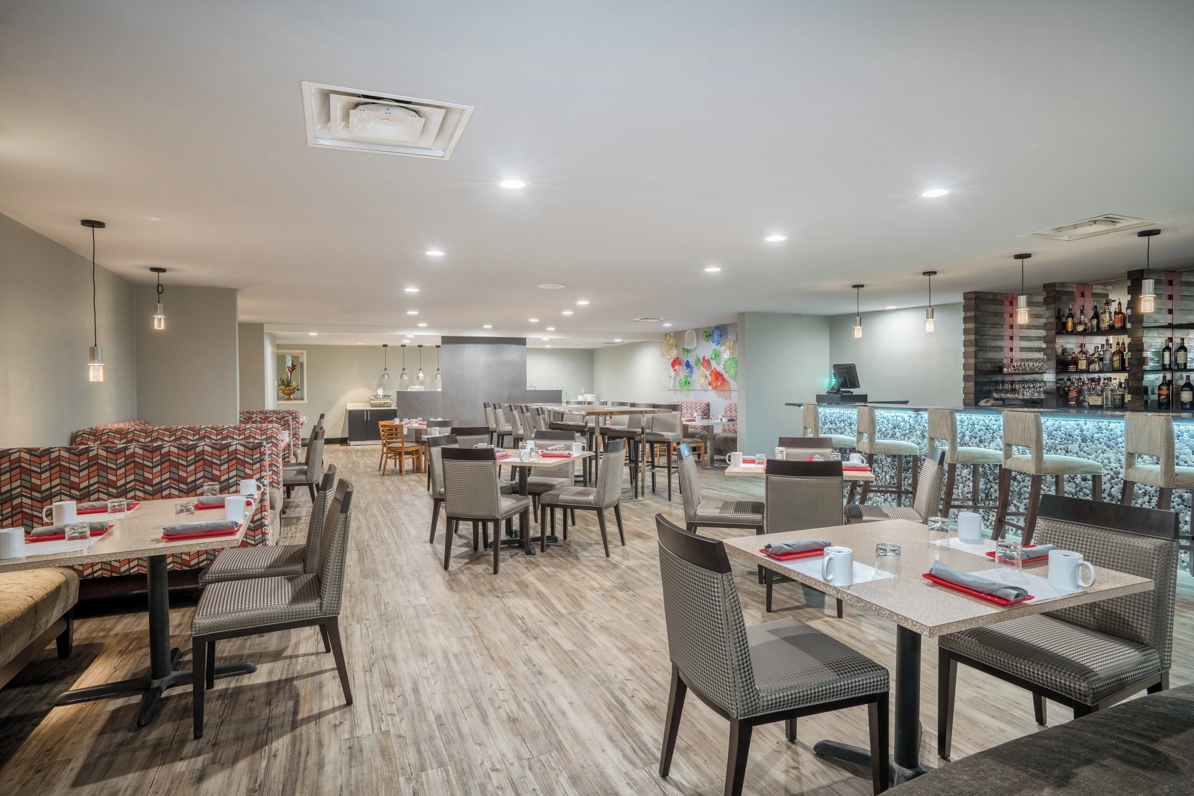 A modern restaurant with multiple dining areas, including a bar with a variety of bottles.