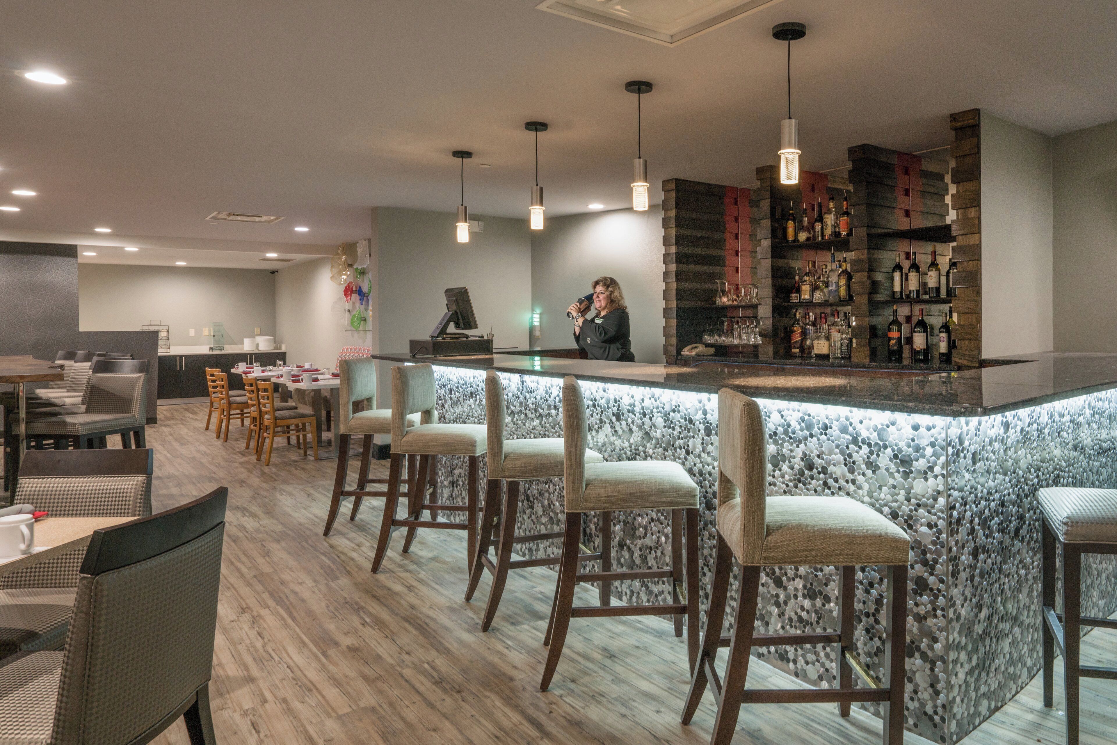 Eine Bar mit Tresen, Barhocker und einer Auswahl an Flaschen.