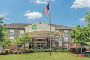 A Holiday Inn hotel with a covered entrance, American flag, and landscaped surroundings.