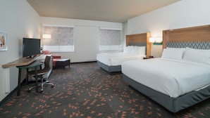 A hotel room with two beds, a desk with a chair, a television, and a carpet with a geometric pattern. - Holiday Inn Atlanta/Roswell by IHG (Roswell)