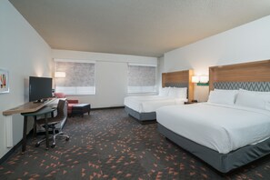 A hotel room with two beds, a desk with a chair, a television, and a carpet with a geometric pattern. - Holiday Inn Atlanta/Roswell by IHG (Roswell)