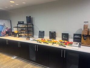 A breakfast buffet area with various food options and a Coca-Cola advertisement. - Holiday Inn Atlanta/Roswell by IHG (Roswell)