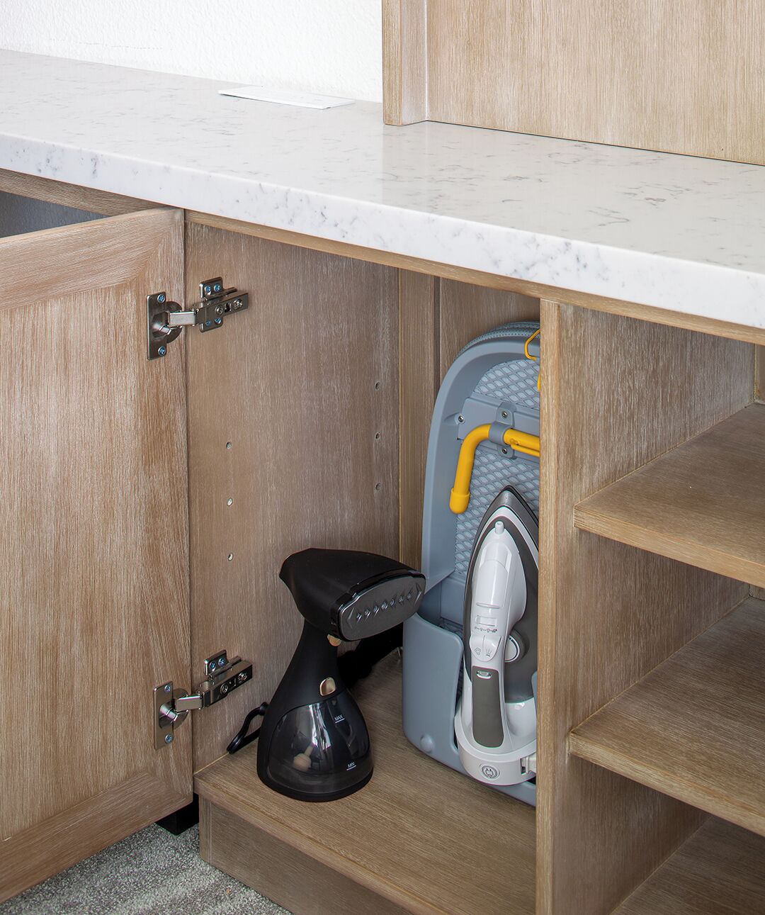 A kitchen with a built-in microwave, a coffee maker, and a compact iron.