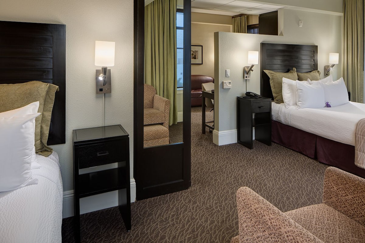 A hotel room with a bed, a desk, a chair, and a mirror.