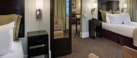 A hotel room with a bed, a desk, a chair, and a mirror.