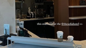 Una Starbucks con un interior moderno, que incluye una pared de madera y una barra con una máquina de café.