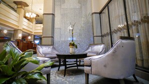 Un hall con zona de estar que incluye dos sillones y una mesa, un muro decorativo y una araña.