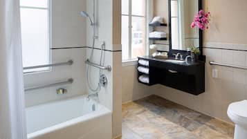 A modern bathroom with a bathtub, a shower, a vanity with a mirror, and a toilet.