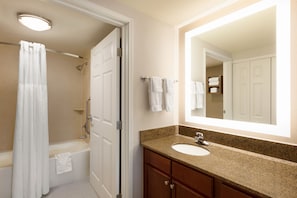 A bathroom with a bathtub, shower, sink, and a large mirror.