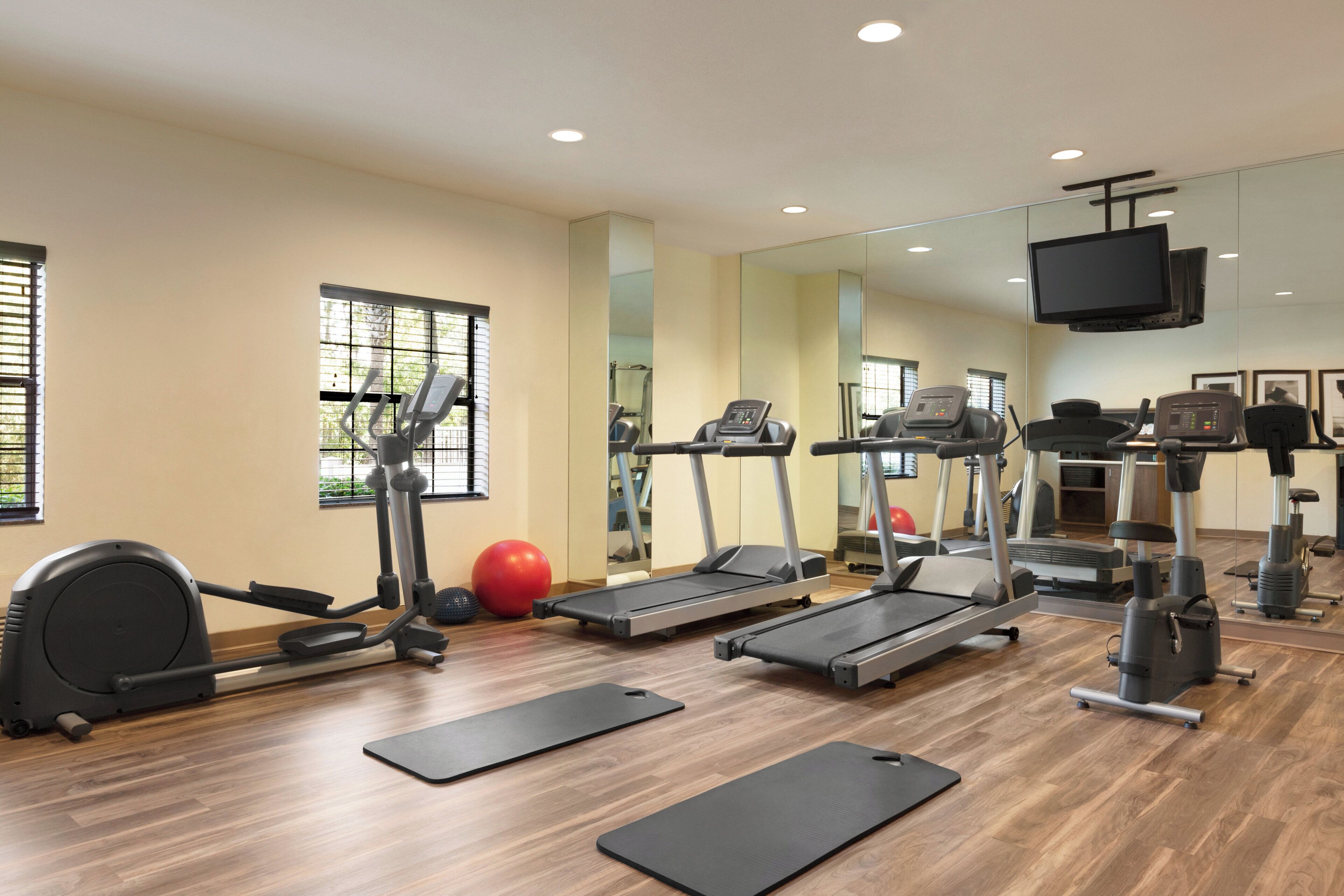 Un gimnasio con cintas de correr, elípticas y pelotas de ejercicio.