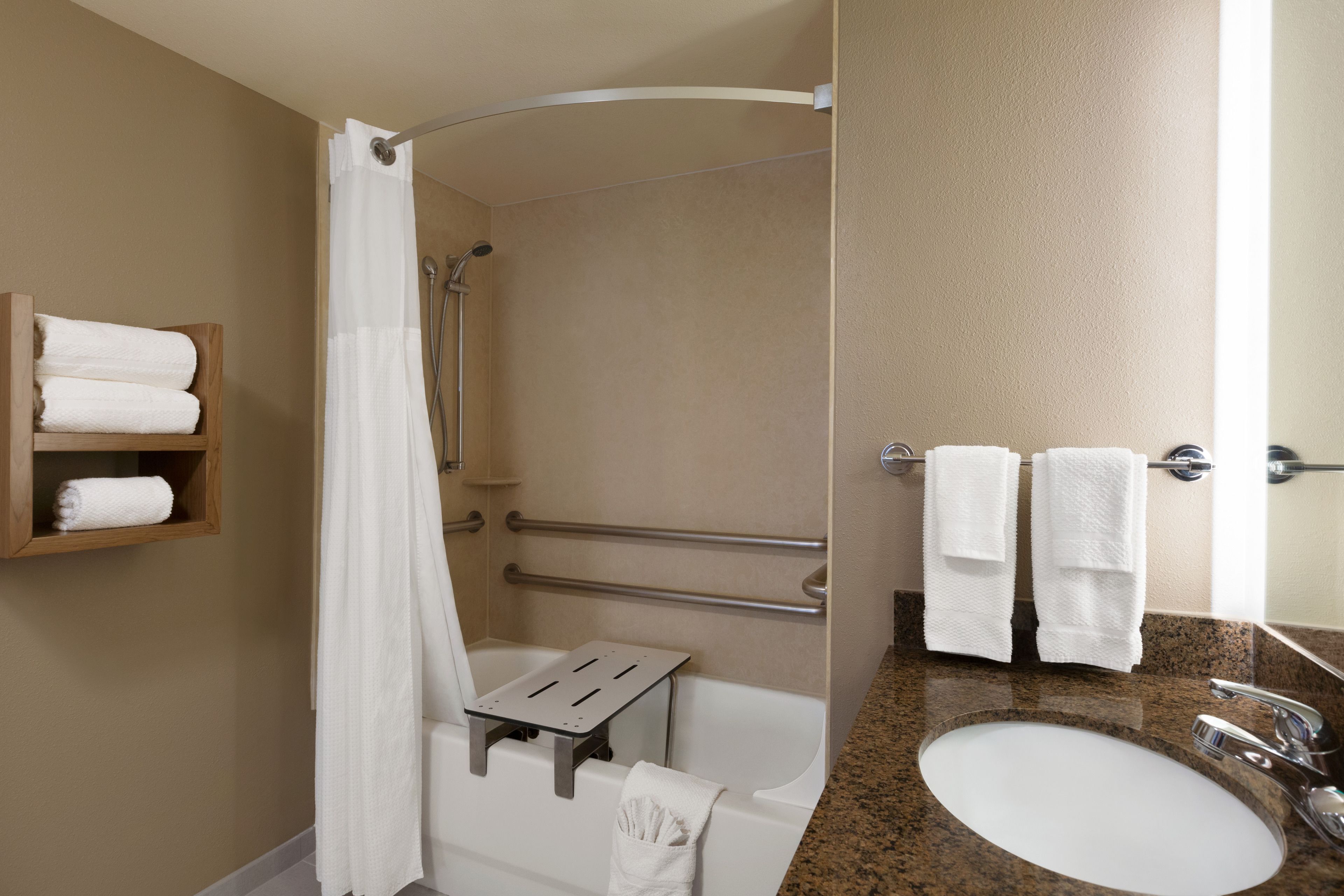 A bathroom with a shower, a sink, and a towel rack.
