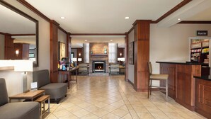 Un hall d’hôtel doté d’une cheminée, d’un coin salon et d’une kitchenette.