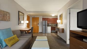 Un espacio habitable compacto con kitchenette, un sofá con cojines, un televisor y un comedor.
