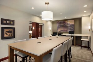 A hotel conference room with a long table, chairs, a large painting, and a computer on a desk. - Staybridge Suites Tampa East - Brandon by IHG (Tampa)