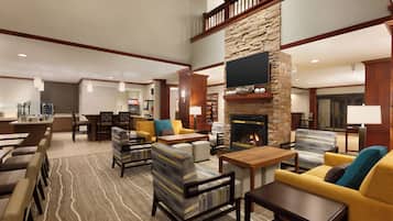 A spacious lobby with a fireplace, seating area, and a television mounted on the wall.