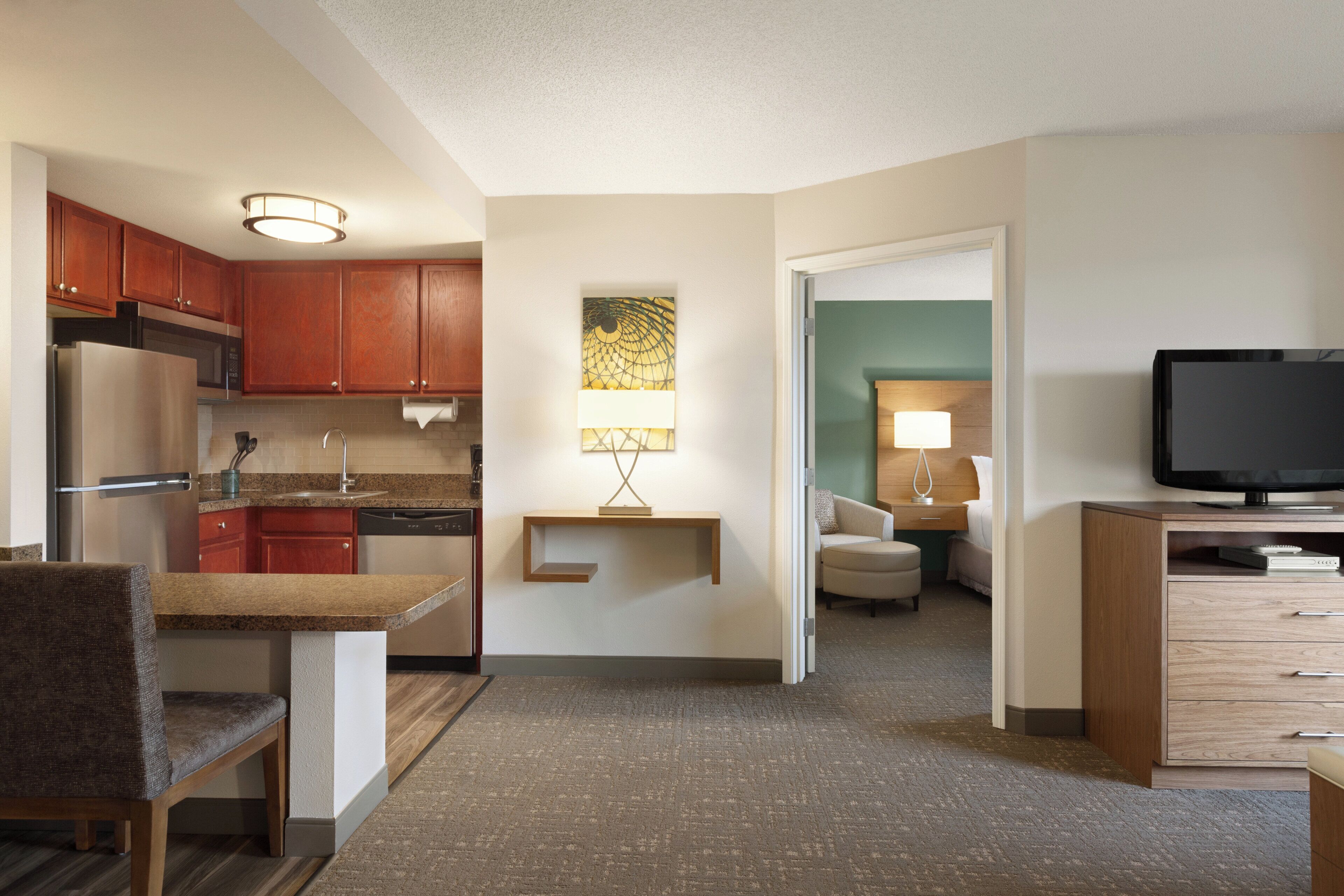 Una habitación de hotel compacta con kitchenette, comedor, sala de estar y televisor.