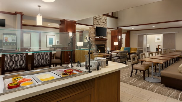 Un espace buffet proposant divers plats, une cheminée en pierre et un coin salon avec des tables et des chaises.