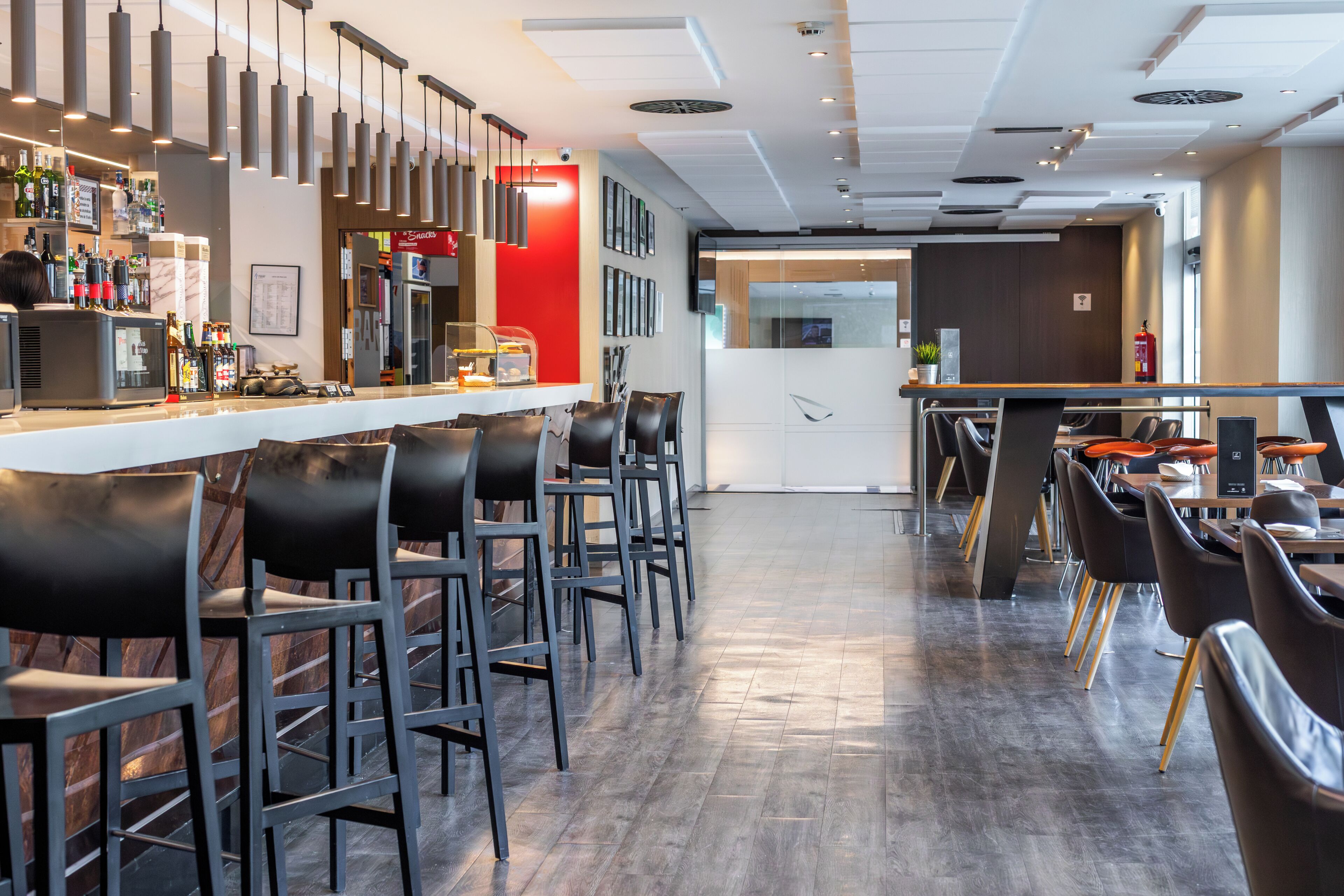 A modern bar area with a counter, bar stools, and a variety of bottles.