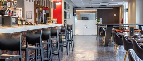 Un espace bar moderne, doté d’un comptoir, de tabourets et d’une variété de bouteilles.
