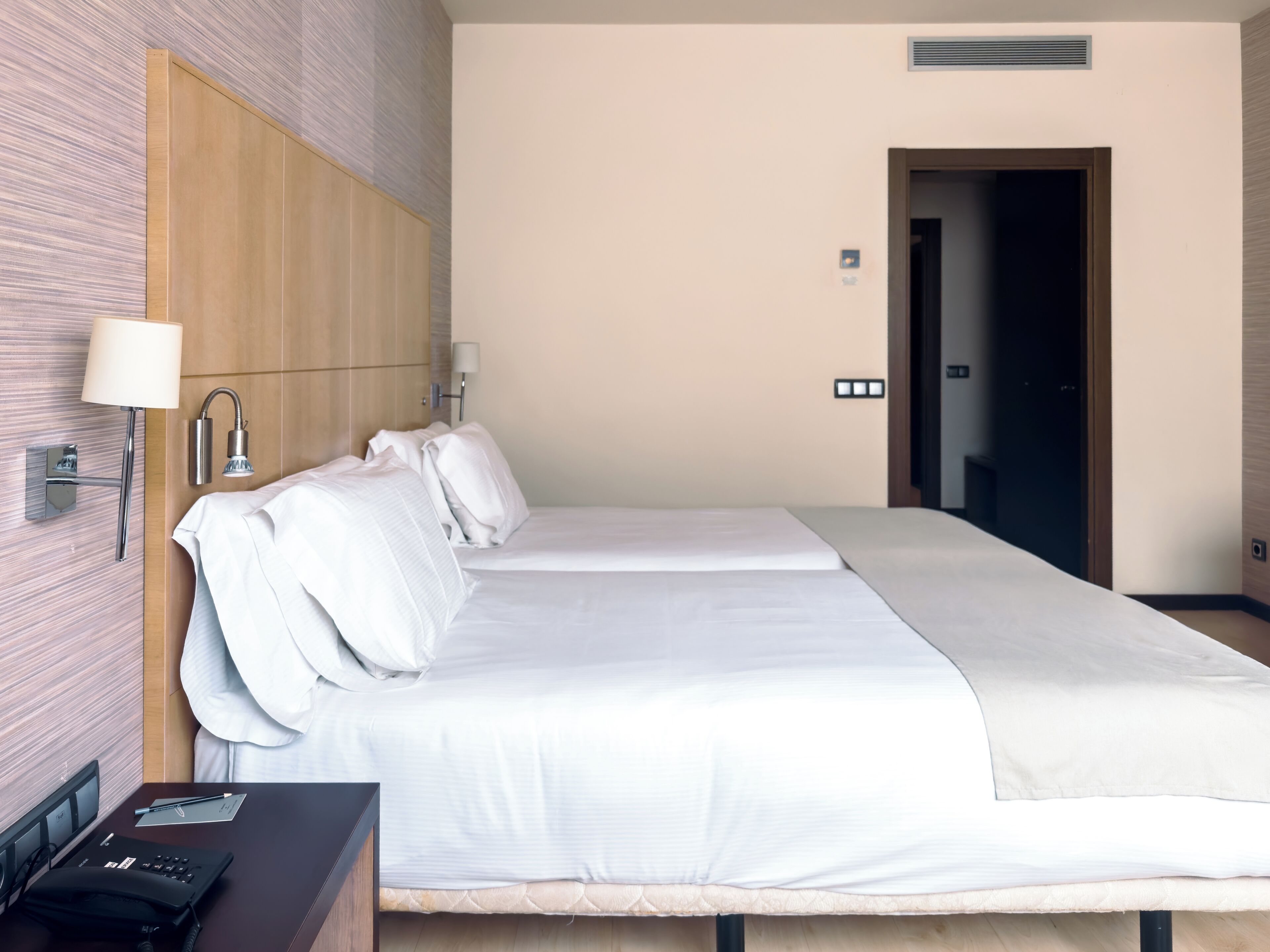 A hotel room with a large bed, a bedside table with a lamp, and a desk with a chair.