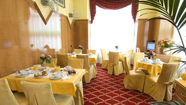 A dining area with tables set for breakfast, featuring yellow tablecloths and matching chairs. - Cinque Giornate (Milan)