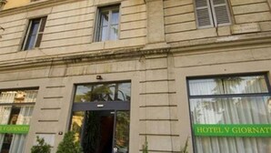 A hotel facade with a classic architectural style, featuring a symmetrical window arrangement and a green sign indicating the hotel's name. - Cinque Giornate (Milan)
