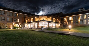 Un hotel con un patio central, numerosas ventanas y una entrada bien iluminada.
