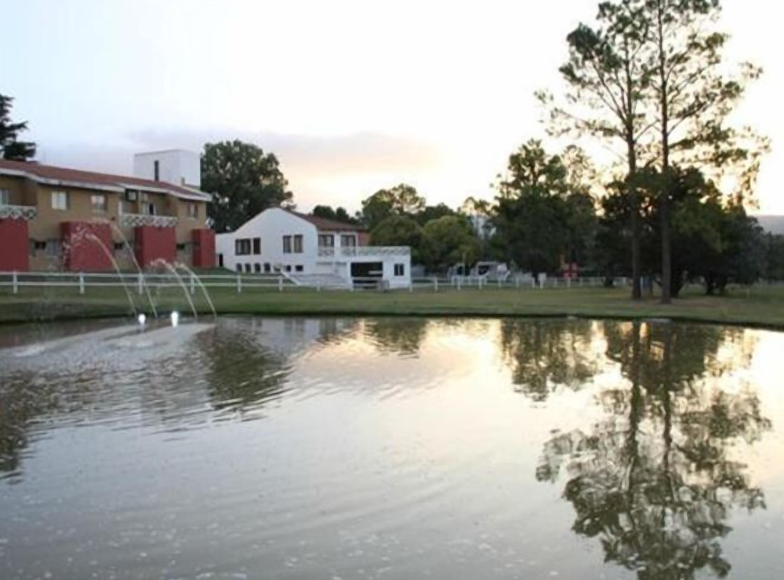 A calm body of water reflecting buildings and trees.