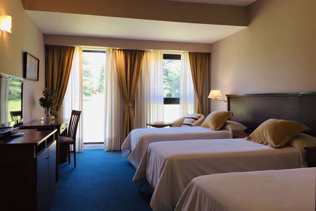 A hotel room with two beds, a desk with a computer, and a chair.