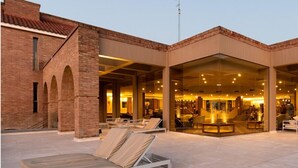 Un hotel con fachada de ladrillo, zona de estar exterior y amplias ventanas de vidrio.