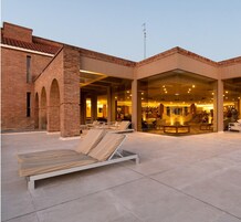 Un hotel con fachada de ladrillo, zona de estar exterior y amplias ventanas de vidrio.