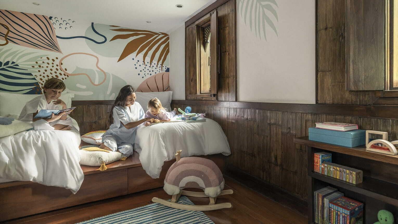 Una habitación con un banco de madera, una estantería y una pared decorada con arte abstracto.