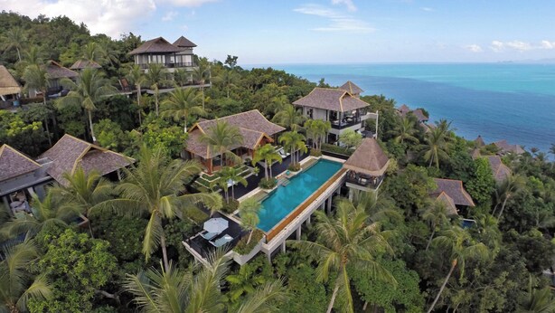 Ein Resort mit mehreren bungalowartigen Gebäuden, einem zentralen Swimmingpool und üppiger tropischer Vegetation.