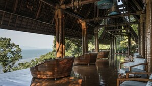 Eine Holzterrasse mit Sitzgelegenheiten und Blick auf den Ozean.