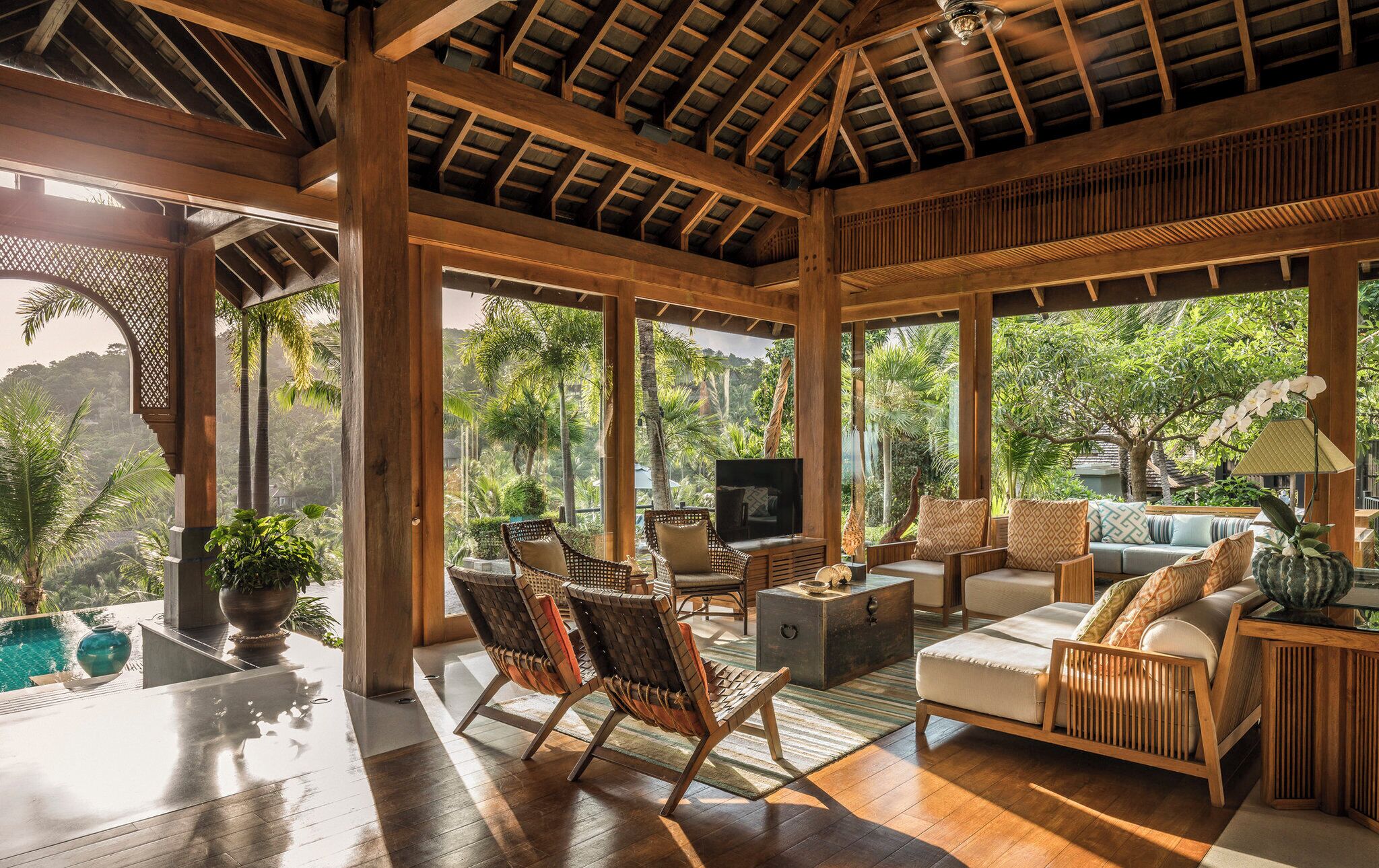 Una habitación amplia con techo de madera, ventanas grandes y vista a exuberante follaje.