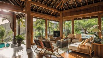 Una habitación amplia con techo de madera, ventanas grandes y vista a exuberante follaje.