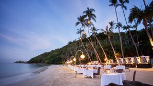 Ein Restaurant direkt am Strand mit Terrassenplätzen, Palmen und Meerblick.