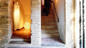 A stone staircase with a person descending, flanked by arched brick walls and a spherical light fixture at the bottom. - Hospes Palacio del Bailío, a Member of Design Hotels (Córdoba)