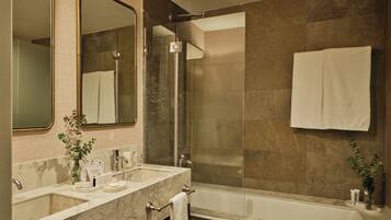A modern bathroom with a glass-enclosed shower, a large mirror, and a marble sink.