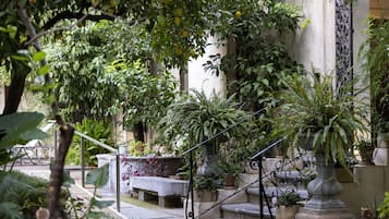 A courtyard with a stone staircase, potted plants, and a bench.