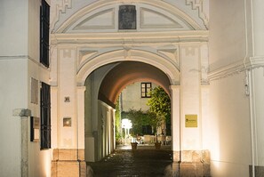 An arched passageway leading to a building with a sign that reads "HOSPES."