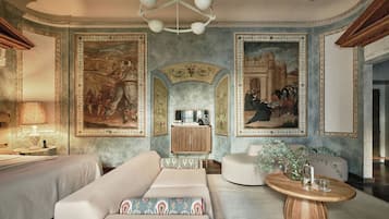 A room with a sofa, a coffee table, and a cabinet. There are paintings on the walls.