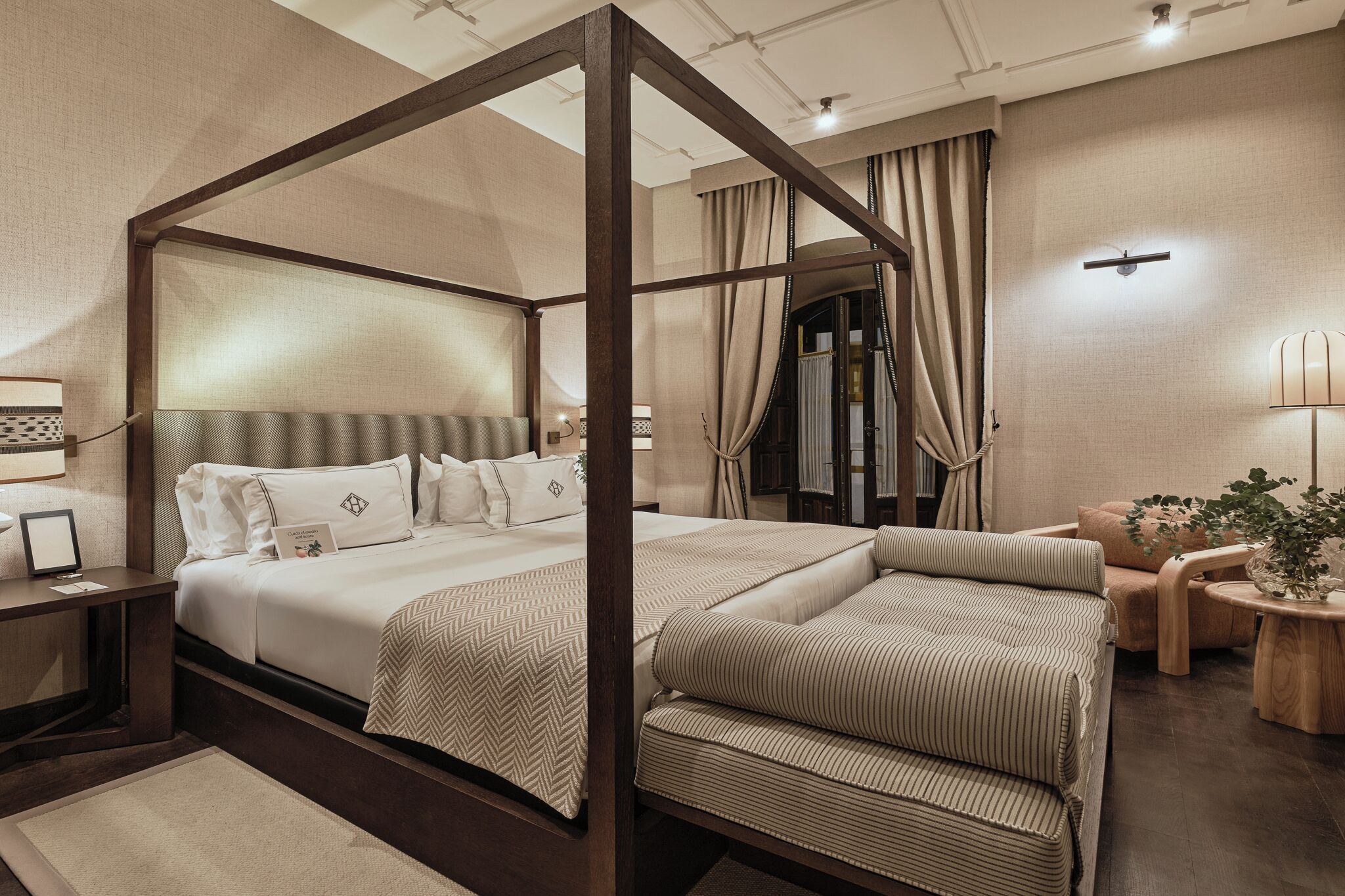 A four-poster canopy bed with a wooden frame, a large mirror, and a bedside table with a lamp.