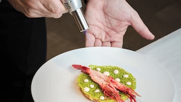 Una persona sosteniendo un plato con un guiso que lleva camarones y guarnición verde.