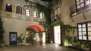 An indoor courtyard with a central archway, potted plants, and a staircase leading to an upper level. - Hospes Palacio del Bailío, a Member of Design Hotels (Córdoba)