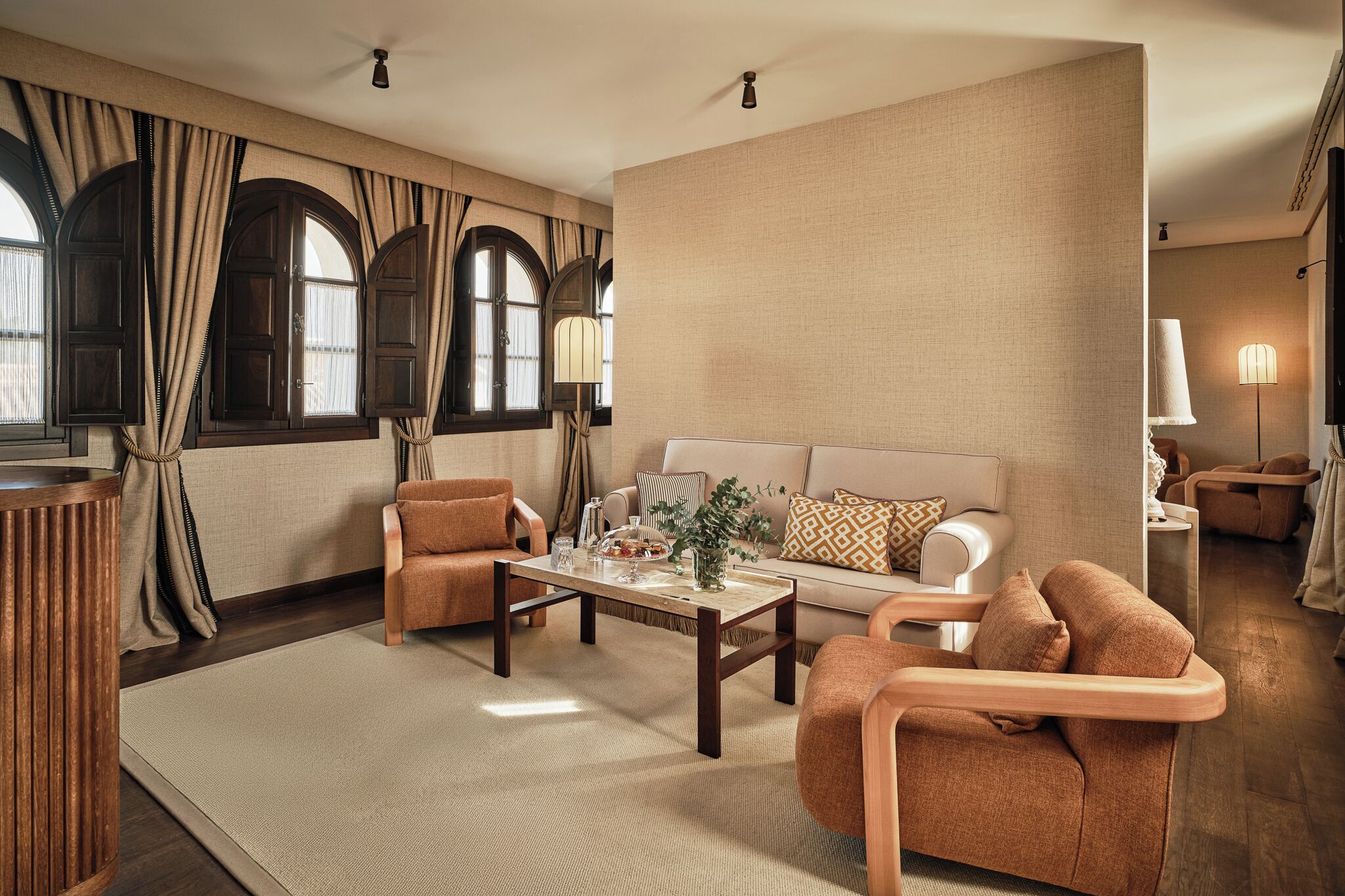 A spacious living room with a sofa, armchairs, a coffee table, and a TV.