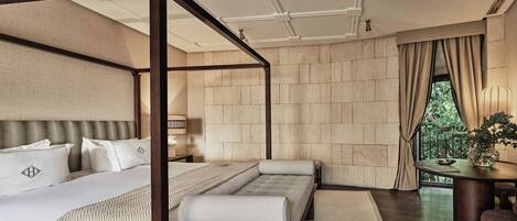 A bedroom with a four-poster bed, a sofa, and a small table with a plant.